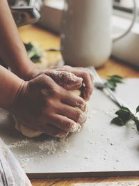 Cropped hands of person making dough on table
