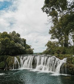 Scenic view of waterfall against sky