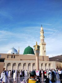 People in front of mosque against sky