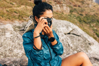 Side view of young man photographing while standing on rock