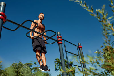 Low angle view of man jumping against sky