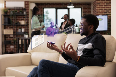 Side view of woman using mobile phone while sitting at home