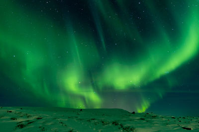 Low angle view of illuminated landscape against sky at night