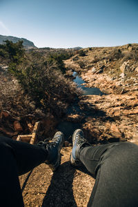 Low section of man sitting on rocky mountain