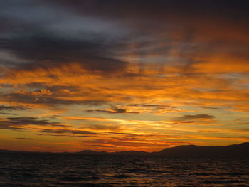 Scenic view of sea against dramatic sky during sunset