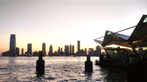 Silhouette buildings in city against clear sky during sunset