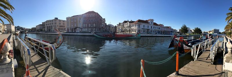 Boats moored in canal against sky in city