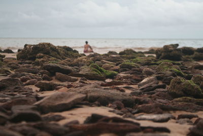 Woman sitting at beach against sky