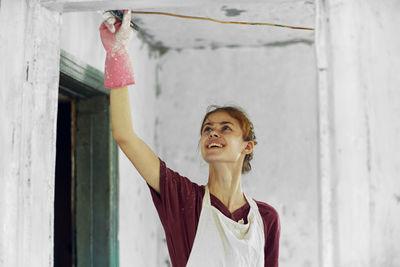 Portrait of young woman standing against wall