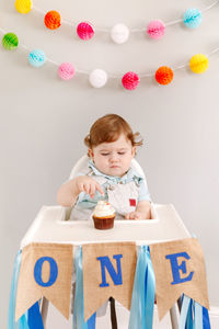 Cute boy looking at birthday cake in home