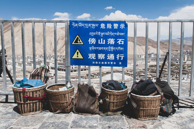 Information sign board on wicker basket against sky