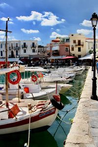 Sailboats moored on canal by buildings in city against sky