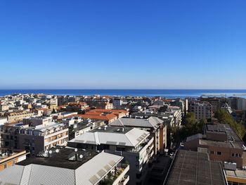 High angle view of buildings and sea against clear blue sky
