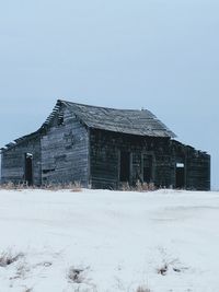 House on field against clear sky during winter