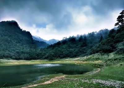 Scenic view of river by mountains against sky