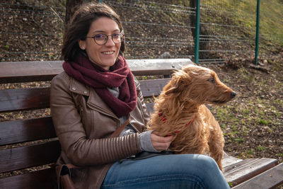 Portrait of smiling woman with dog sitting outdoors