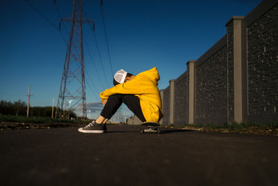 Teen boy with head down sitting on skateboard