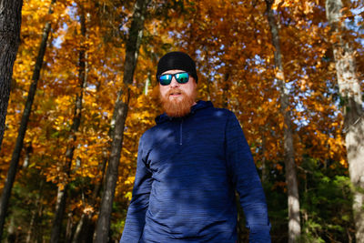 Man wearing sunglasses standing by trees during autumn