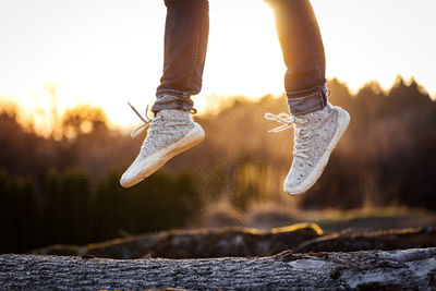 Low section of person jumping against sky