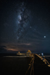 Illuminated bridge over sea against sky at night