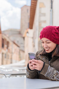 Smiling woman using smart phone at table