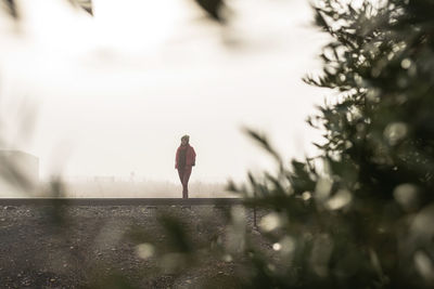 Thoughtful woman standing on a foggy railroad while looking away