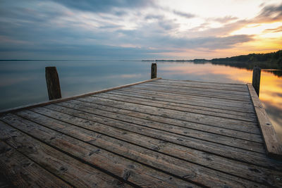 Wooden pier over sea against sky during sunset