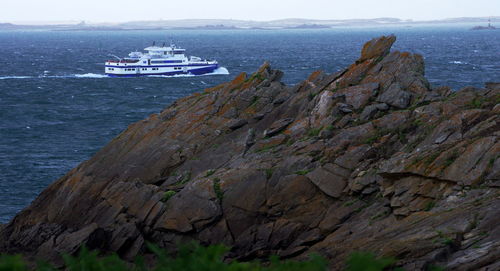 Boat sailing on sea by mountain against sky