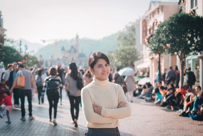 Portrait of woman with arms crossed standing in city