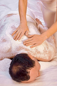 A woman healer performs a ritual with salt, rubs the back of a lying man with salt. 