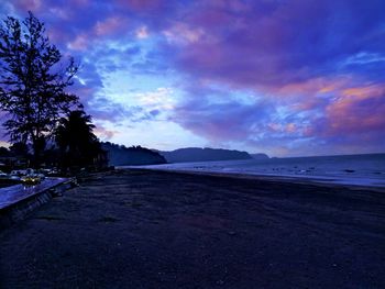 Scenic view of beach against sky at sunset