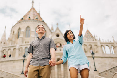 Couple holding hands while standing against church