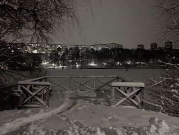 Snow covered land by building against sky at night