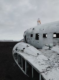 Damaged airplane on beach against sky