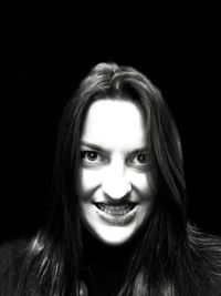 Portrait of smiling woman against black background