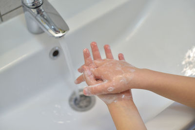 High angle view of hands touching water in bathroom