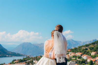 Rear view of couple standing on mountain against sky