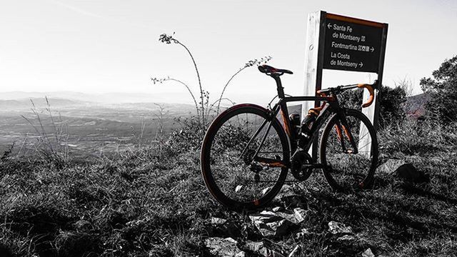 bicycle, text, tree, transportation, field, land vehicle, landscape, western script, communication, sky, mode of transport, tranquility, tranquil scene, plant, nature, grass, growth, stationary, clear sky, day