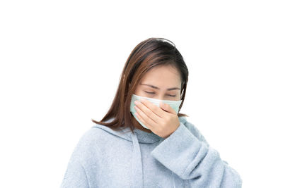 Portrait of woman covering face against white background