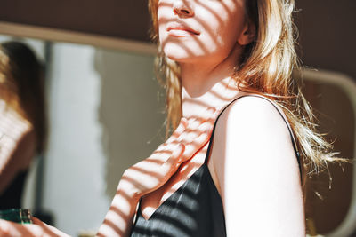 Young woman in black dress put body cream on clean fresh skin in bathroom at home