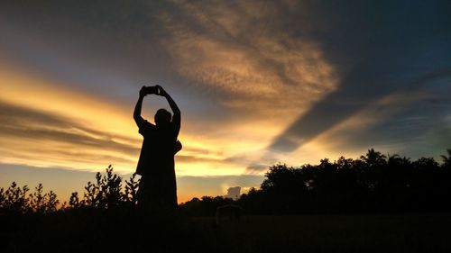 Silhouette man on field against sky during sunset