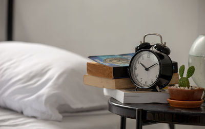 Close-up of alarm clock by bed on table at home