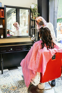 Rear view of woman standing by window