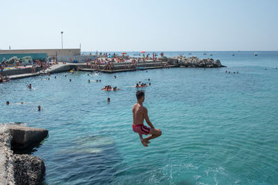 Man jumping in sea against clear sky