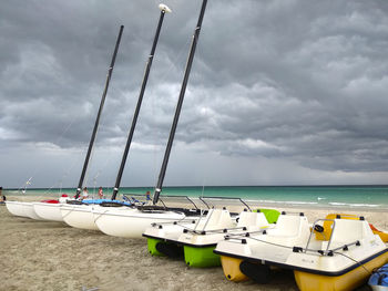 Sailboats moored in sea against sky