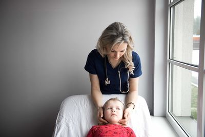Pediatrician examining cute girl in medical clinic