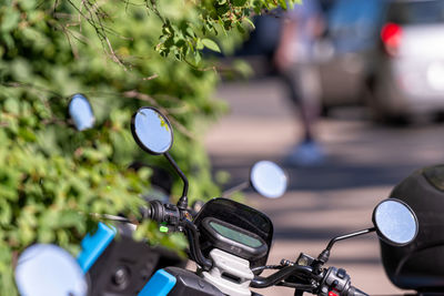 Many street-side scooter mirrors parked against a defocused urban background, closeup