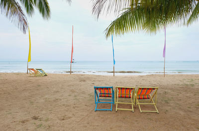 Chairs and tables on beach against sky