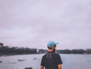 Rear view of man looking at lake against sky