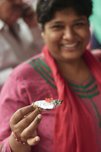 Close-up portrait of smiling woman holding food